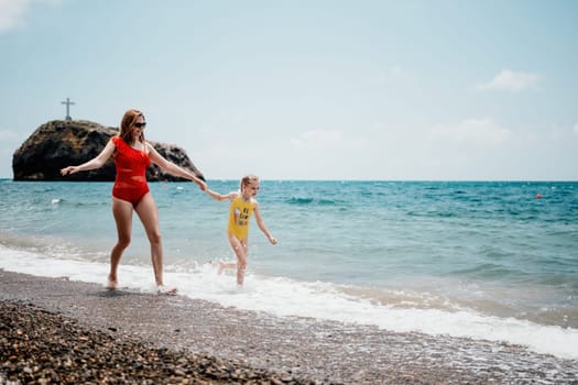 Happy loving family mother and daughter having fun together on the beach. Mum playing with her kid in holiday vacation next to the ocean - Family lifestyle and love concept.