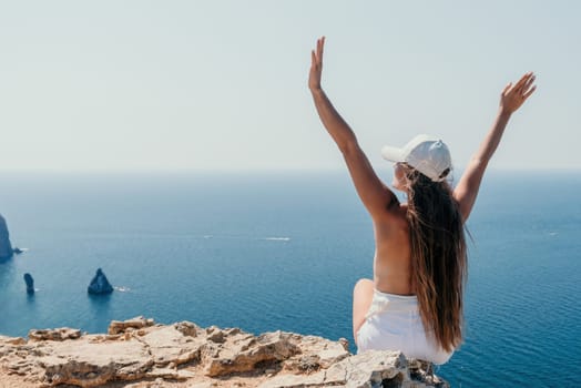 Woman travel sea. Young Happy woman in a long red dress posing on a beach near the sea on background of volcanic rocks, like in Iceland, sharing travel adventure journey