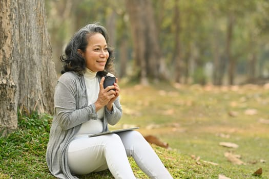 Elegant elderly woman drinking coffee and enjoy outdoor leisure activity on a warm day. Authentic senior retired life concept.