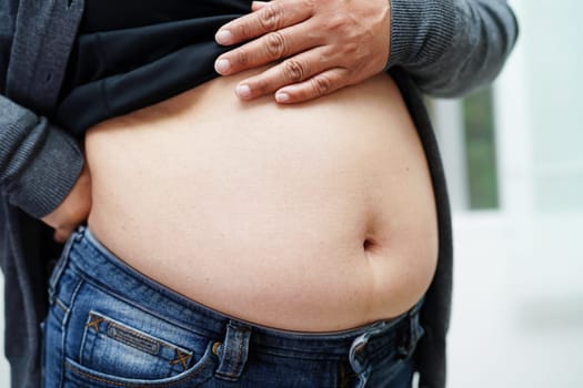 Overweight asian woman use hand to squeeze fat belly big size overweight and obesity.