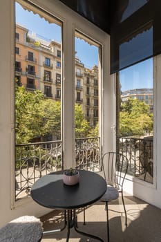 Amazing view of two chairs and coffee table on covered terrace with stunning views of the Barcelona area on sunny warm summer day. Concept of an apartment for a young family
