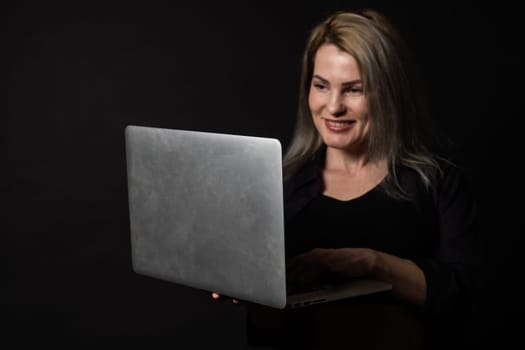 woman with laptop on black background.