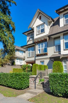 Paved pathway to the entrance of residential townhouse on sunny day.