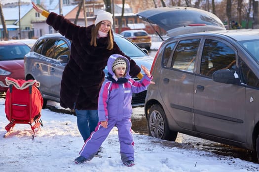 a group of one or more parents and their children living together as a unit. Happy and satisfied mother with a child after a walk in the park near their car.