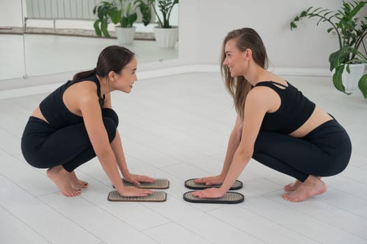 Caucasian and Asian women keep their hands on sadhu boards. Nailing practice