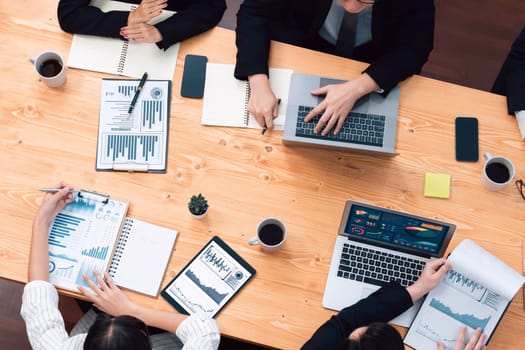 Top-view closeup business team of financial data analysis meeting with business intelligence, report paper and dashboard on laptop. Business group people working together in harmony office.