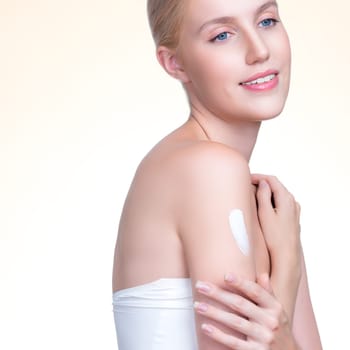 Closeup personable beautiful woman putting skincare moisturizer cream on her arm looking in camera in isolated background as concept for beauty care treatment. Female model applying lotion on her body