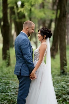 wedding walk of the bride and groom in the deciduous forest in summer