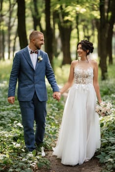 wedding walk of the bride and groom in the deciduous forest in summer