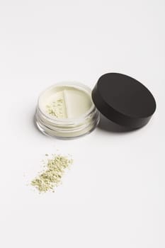 Green cosmetic mineral powder for face on container with twist seal sifter - top view isolated on white