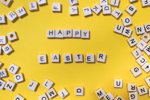  inscription on wooden cubes happy easter on yellow background. creative festive background with scattered letters