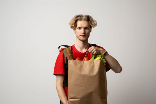 Paper food containers in hands of a smiling deliveryman in a red uniform. Quality service of a restaurant