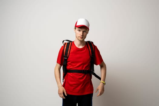 Delivery man in a red uniform carry thermal backpack full of food, groceries to the clients. Food delivery service