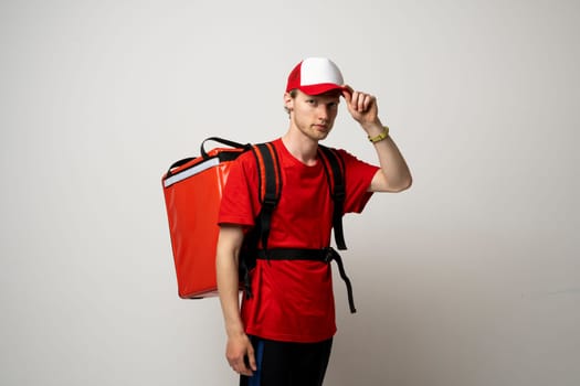 Delivery man in red uniform with thermal backpack for food. Takeaway food delivery. Man delivering online food orders to customers with red thermal bag, grocery deliver