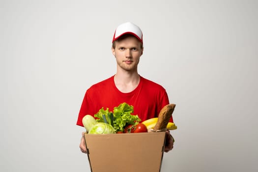 Delivery man in a red uniform holding paper box and delivering food to customer at doorway