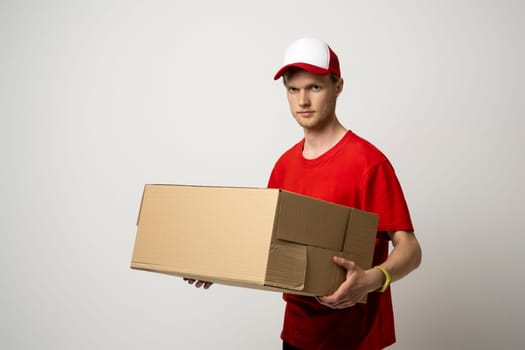 Courier man in red uniform carrying a box, parcel on white background. Delivery service, post