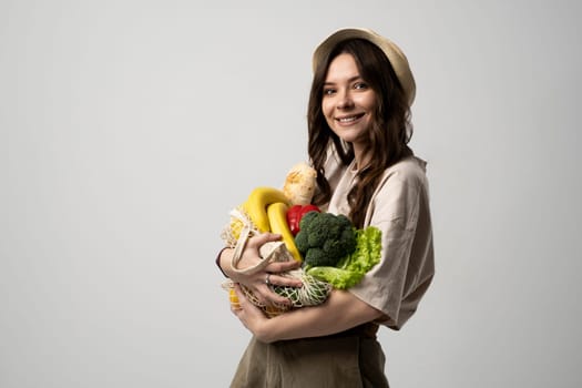 Young woman holding mesh grocery bag with vegetables Concept of no plastic. Zero waste, plastic free. Eco friendly concept. Sustainable lifestyle