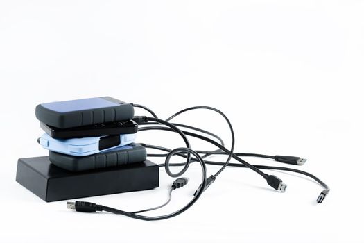 many external hard drives with wires lie on a white background. Hard drives on isolate