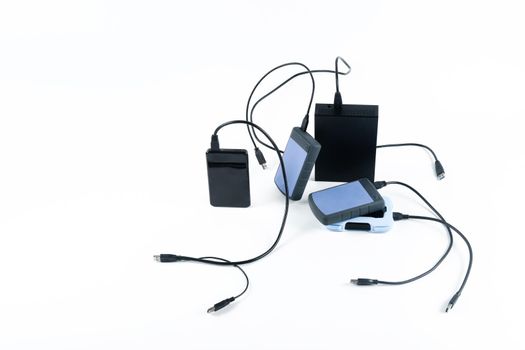 many external hard drives with wires lie on a white background. Hard drives on isolate