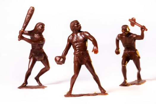 Large toy figures of primitive people on a white background.