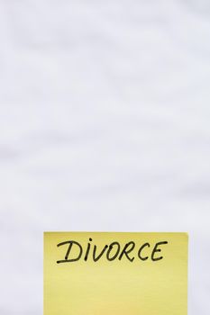Divorce handwriting text close up isolated on yellow paper with copy space.