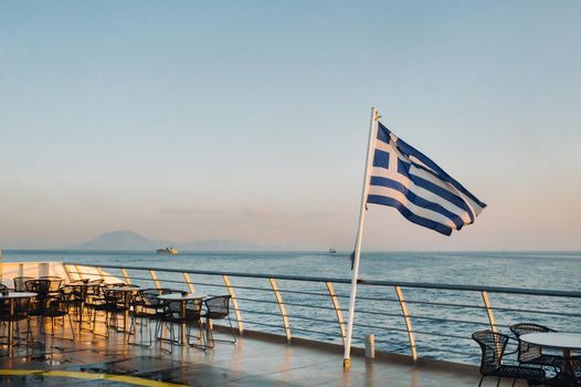 A large ferry at dawn in the Mediterranean Sea with a Greek flag on board.Greece.