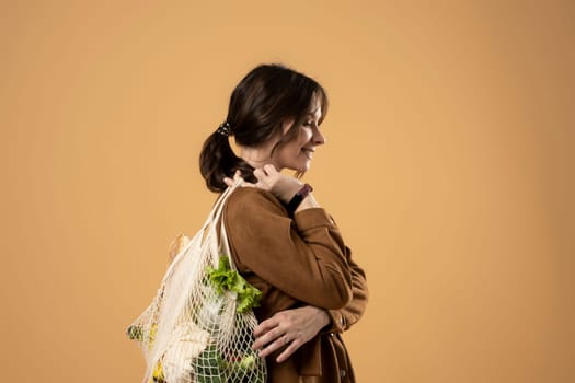 Women holds mesh bag with vegetables, fruits and groceries. Concept of no plastic. Zero waste, plastic free. Eco friendly concept. Sustainable lifestyle