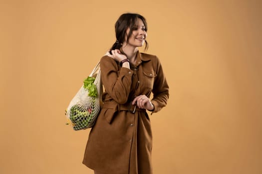 Reusable eco bag for shopping. String shopping bag with fruits and vegetables in the hands of a young woman. Zero waste, plastic free concept. Eco lifestyle. Eco shopping