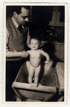 HODONIN, THE CZECHOSLOVAK REPUBLIC, CIRCA 1940: A vintage photo shows father with baby girl. He takes a bath her, circa 1940.