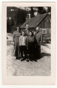 THE CZECHOSLOVAK SOCIALIST REPUBLIC, CIRCA 1950: A vintage photo shows group of people In front of a log house in winter, circa 1950s.