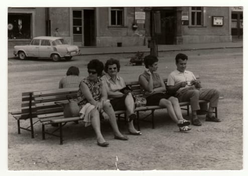 THE CZECHOSLOVAK SOCIALIST REPUBLIC, 1960: Retro photo shows a group of people sits on benches outdoor, 1960s.