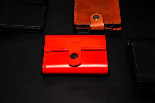 A set of handmade leather wallets. Black, brown, red. Leather craft. Men's wallets on a dark background. View from above.