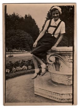 THE CZECHOSLOVAK REPUBLIC -CIRCA 1930s: A vintage photo shows young woman sits on a big stone flowerpot in a city park, circa 1930s.
