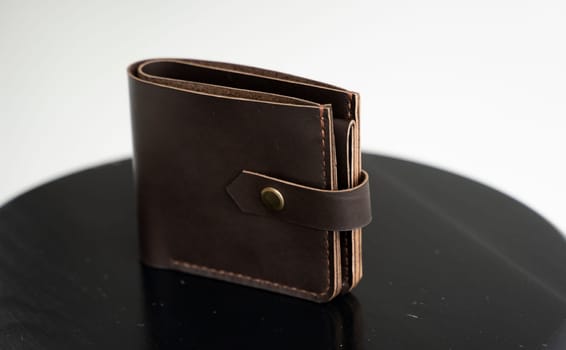 New brown genuine leather wallet on a wooden black chair with white background. Men's accessories