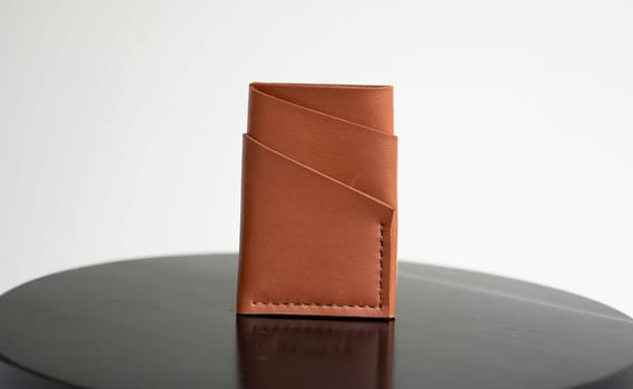 Close up orange men's business leather card holder on a black chair with a white background. Men's accessories