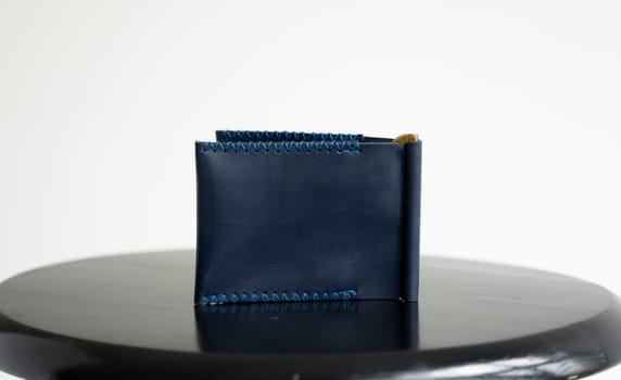 Empty blue men's money clip handmade leather wallet with a two pockets on a black table. Selective focus, copy space, Close up