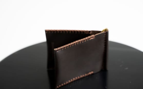 Handmade brown men's money clip handmade leather wallet with a two pockets on a black table. Selective focus, copy space, Close up
