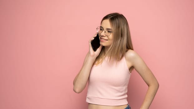 Young blonde woman over isolated pink background sending a message with the mobile