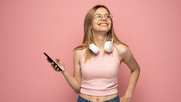 Young blonde woman in a glasses and pink t-shirt over isolated pink background sending a message with the mobile