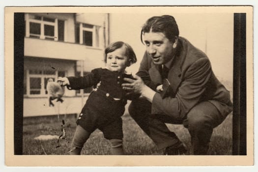 PRAGUE, THE CZECHOSLOVAK SOCIALIST REPUBLIC - CIRCA 1950s: Vintage photo shows father with child and plush toy (stuffed animal).