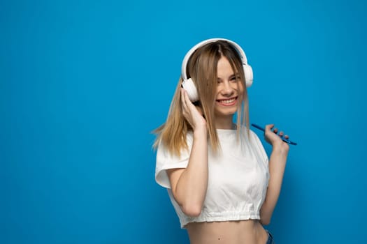 Happy young blonde woman in headphones with smartphone listening to the music