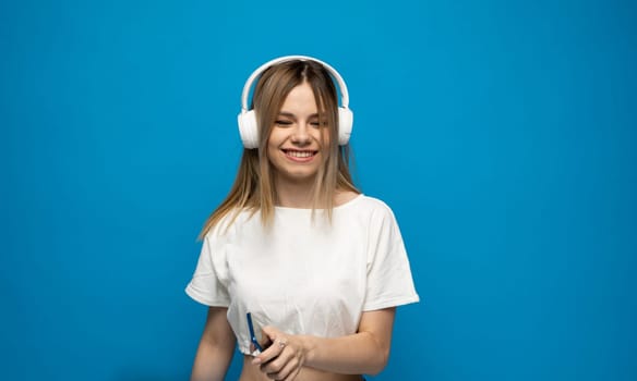 Close-up portrait of attractive lovely charming cheerful blonde girl meloman listening music isolated on blue color background
