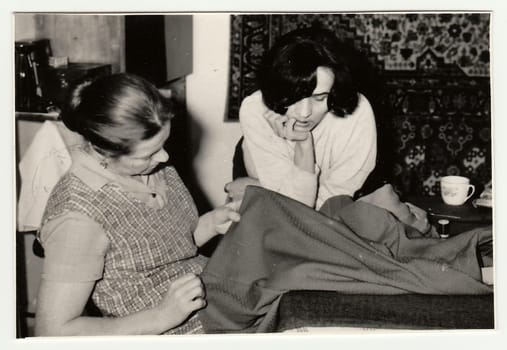 USSR - CIRCA 1970s: Vintage photo shows women prepare to sew a dress.
