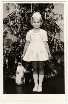 USSR - CIRCA 1980s: Vintage photo shows a small girl (about 7 years old) in front of Christmas tree.