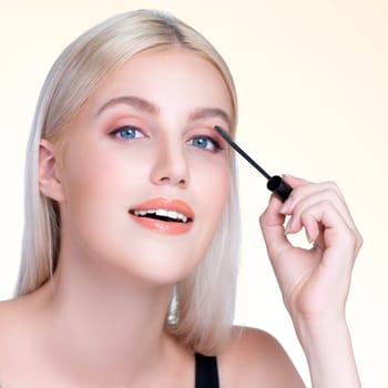 Closeup personable woman with blond hair putting black mascara with brush in hand on long thick eyelash. Perfect fashionable cosmetic clean facial skin with beautiful eye young woman.
