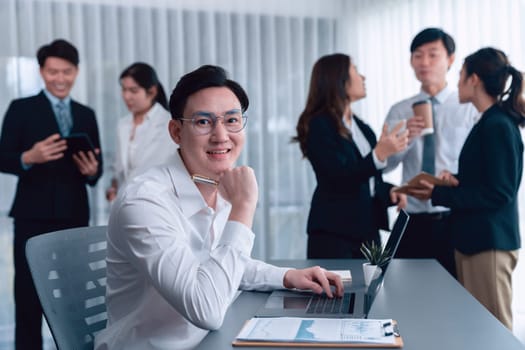 Portrait of focus young successful confident male manager, executive wearing business wear in harmony office arm crossed with blurred meeting background of colleagues, office worker.