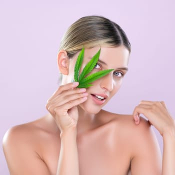 Alluring beautiful woman model portrait holding green leaf as concept for cannabis skincare cosmetic product for perfect skin freshness treatment in isolated pink background.