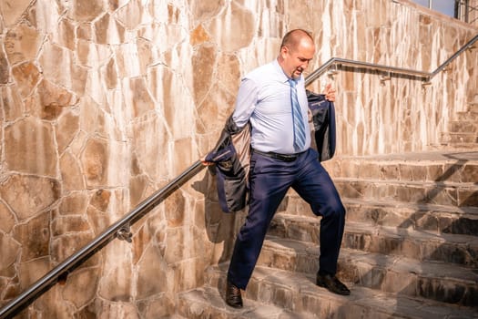 Portrait of a senior professional man in a suit with various problems. A middle-aged businessman with a briefcase descends the stairs.