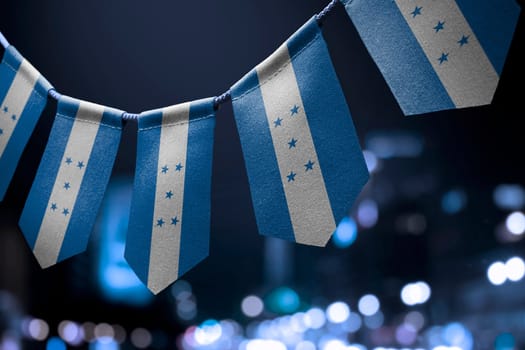 A garland of Honduras national flags on an abstract blurred background.
