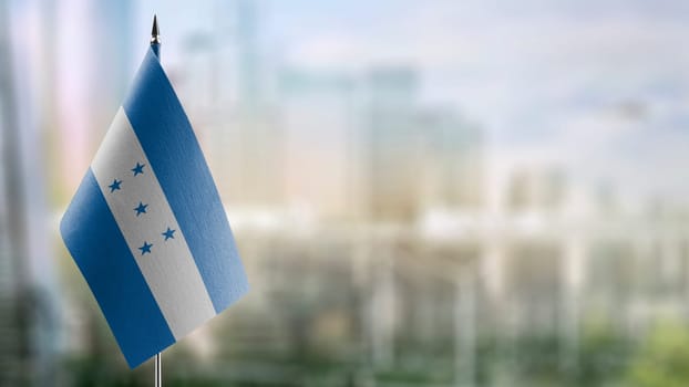 Small flags of the Honduras on an abstract blurry background.